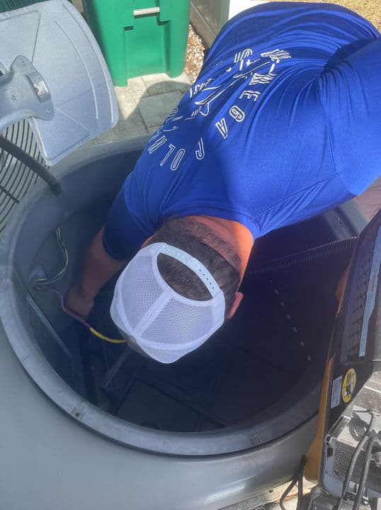 Mega Cooling technician servicing an outdoor condenser